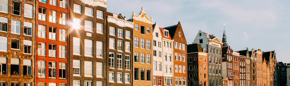 Row of traditional Dutch canal houses in Amsterdam illuminated by late-afternoon sunlight